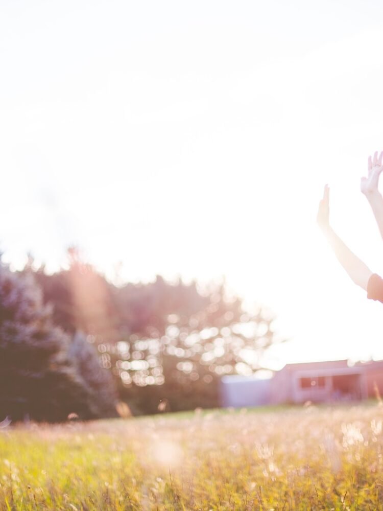 woman hands up in front of green meadows